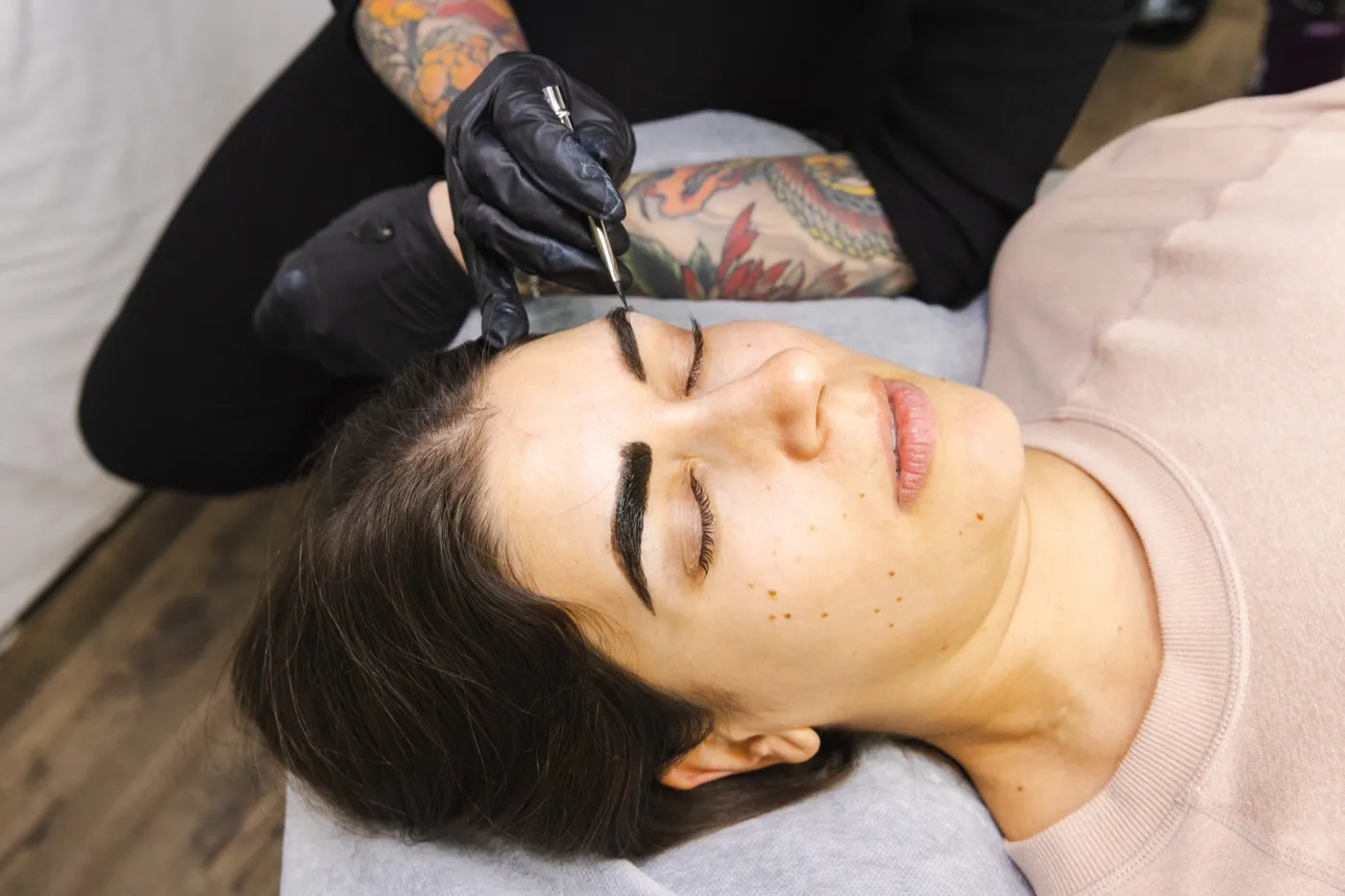 Una artista perfila el tinte oscuro de cejas con un pincel fino.